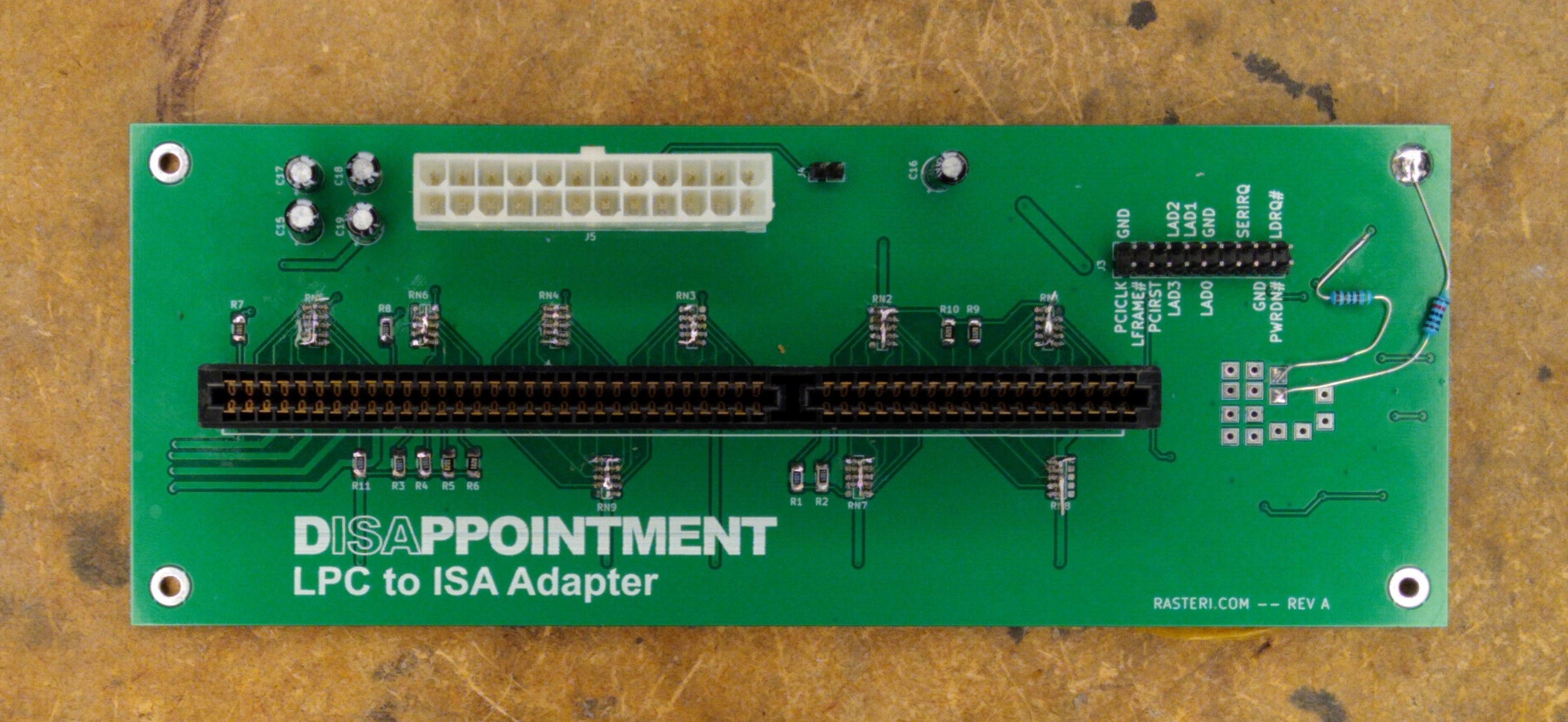 A green PCB with an ISA card slot and various connectors and components. The text "DISAPPOINTMENT LPC to ISA Adapter" is printed in the bottom left of the board.